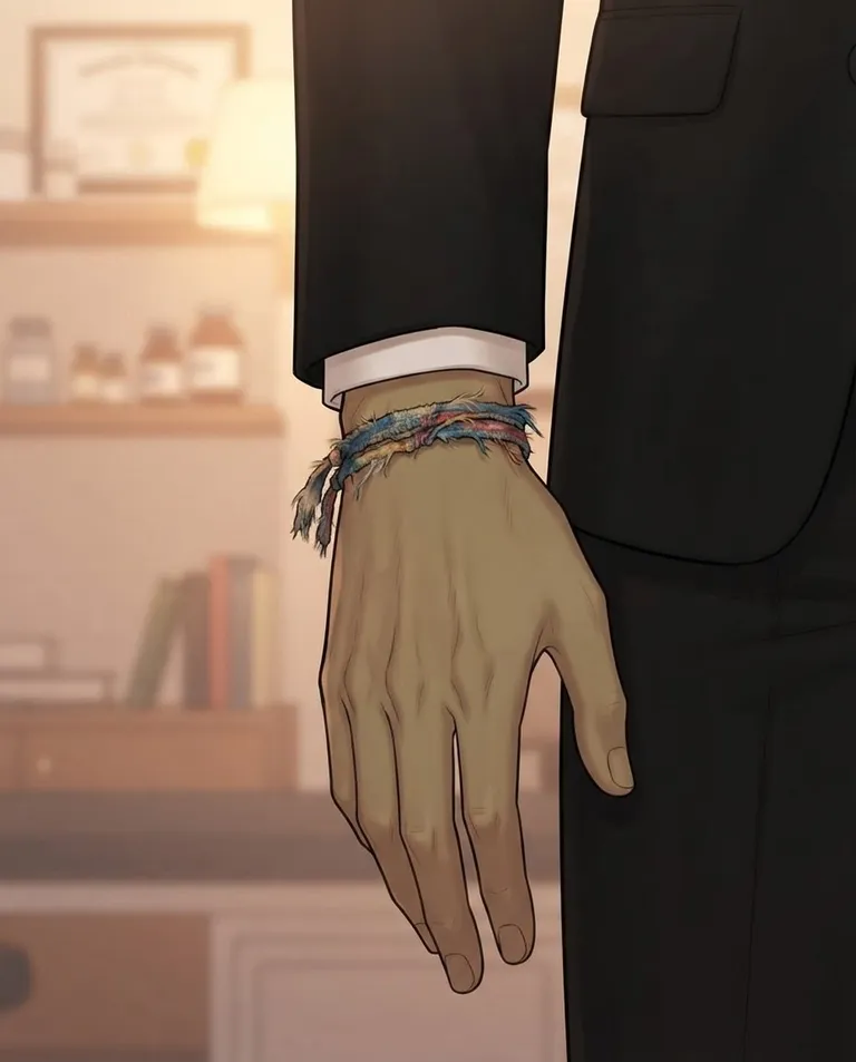 Polished manhwa character art, simple background: close shot of the wrist and hand of Gabriel, a young adult man with slicked-back black hair with a few loose strands, dark umber eyes, olive skin and a tall broad-shouldered build, wearing a tailored black suit over a white dress shirt with the top button undone, a frayed handmade woven bracelet in faded thread on his right wrist, the worn childhood bracelet in sharp focus against the crisp black suit cuff, his fingers relaxing open, soft blurred clinic shelves behind. Gentle warm lamplight with shallow depth of field. Tender nostalgic amber-and-cream palette. No text, no watermark.